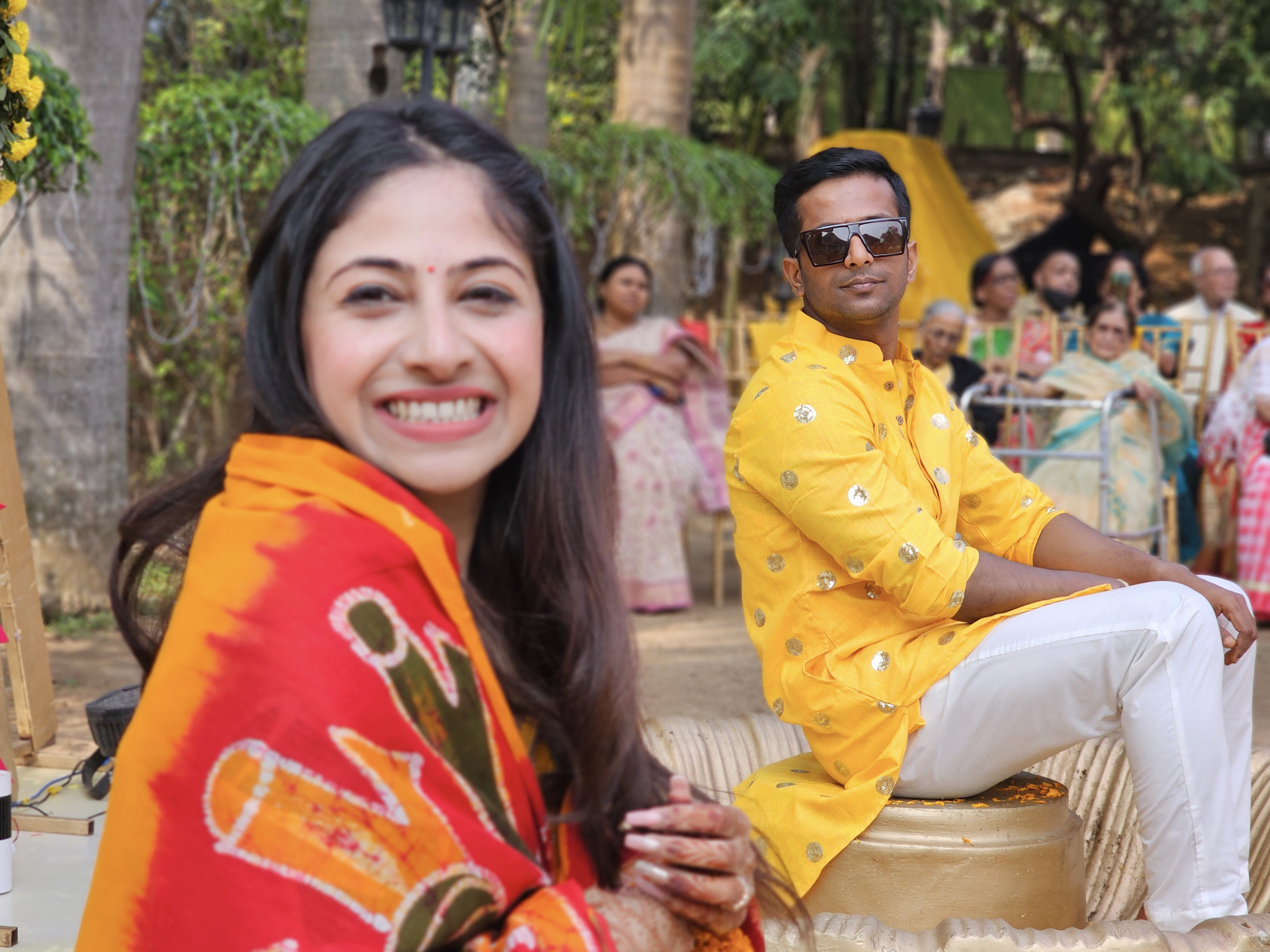 Concentre-se no noivo indiano e na noiva indiana fora de foco com os participantes de um casamento indiano em segundo plano capturado com a câmera telefoto 3x no modo retrato do Samsung Galaxy S23 Ultra.