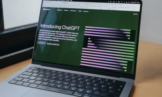 A MacBook Pro on a desk with ChatGPT's website showing on its display.