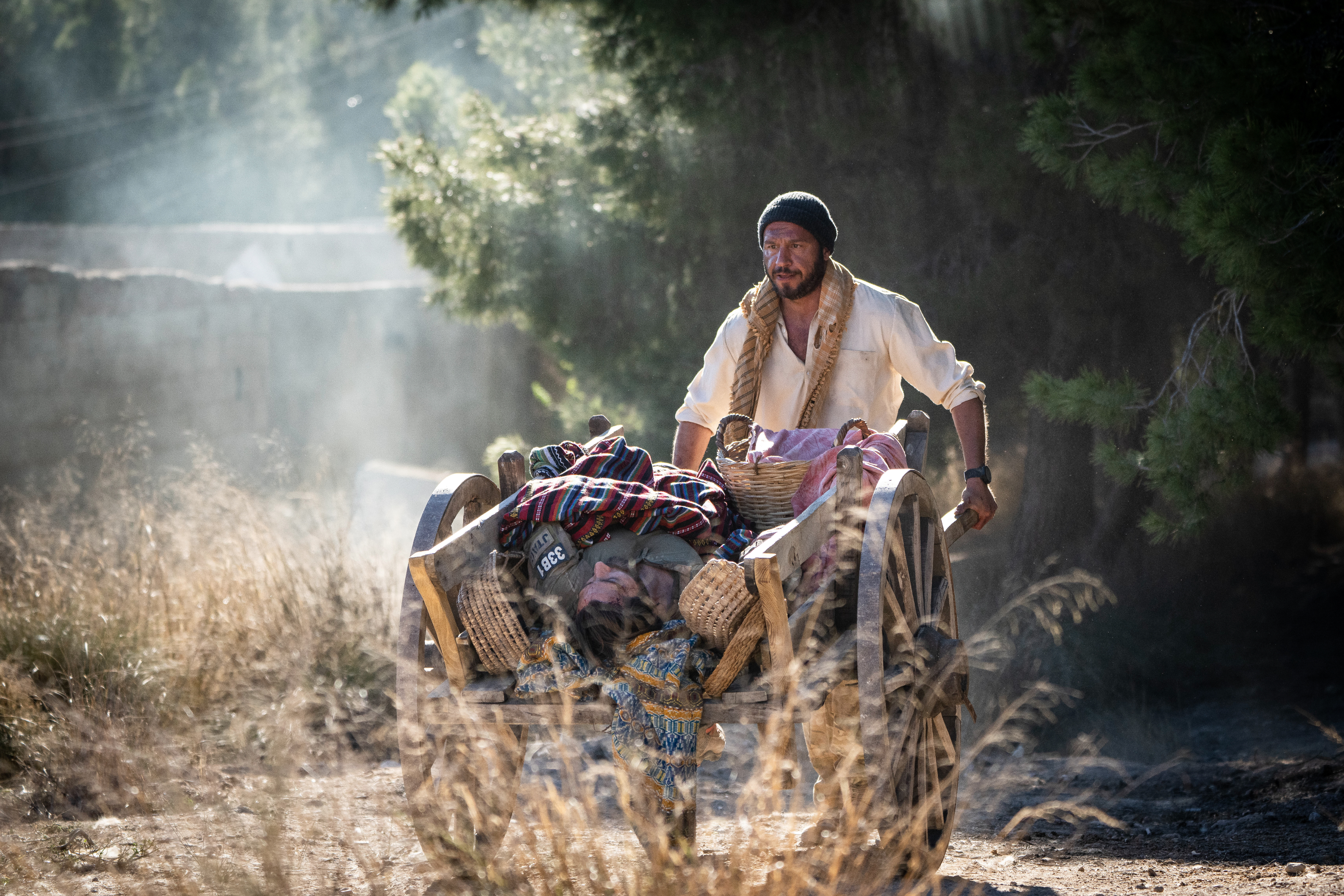 Dar Salim empurra Jake Gyllenhaal em um carrinho de madeira em The Covenant, de Guy Ritchie.