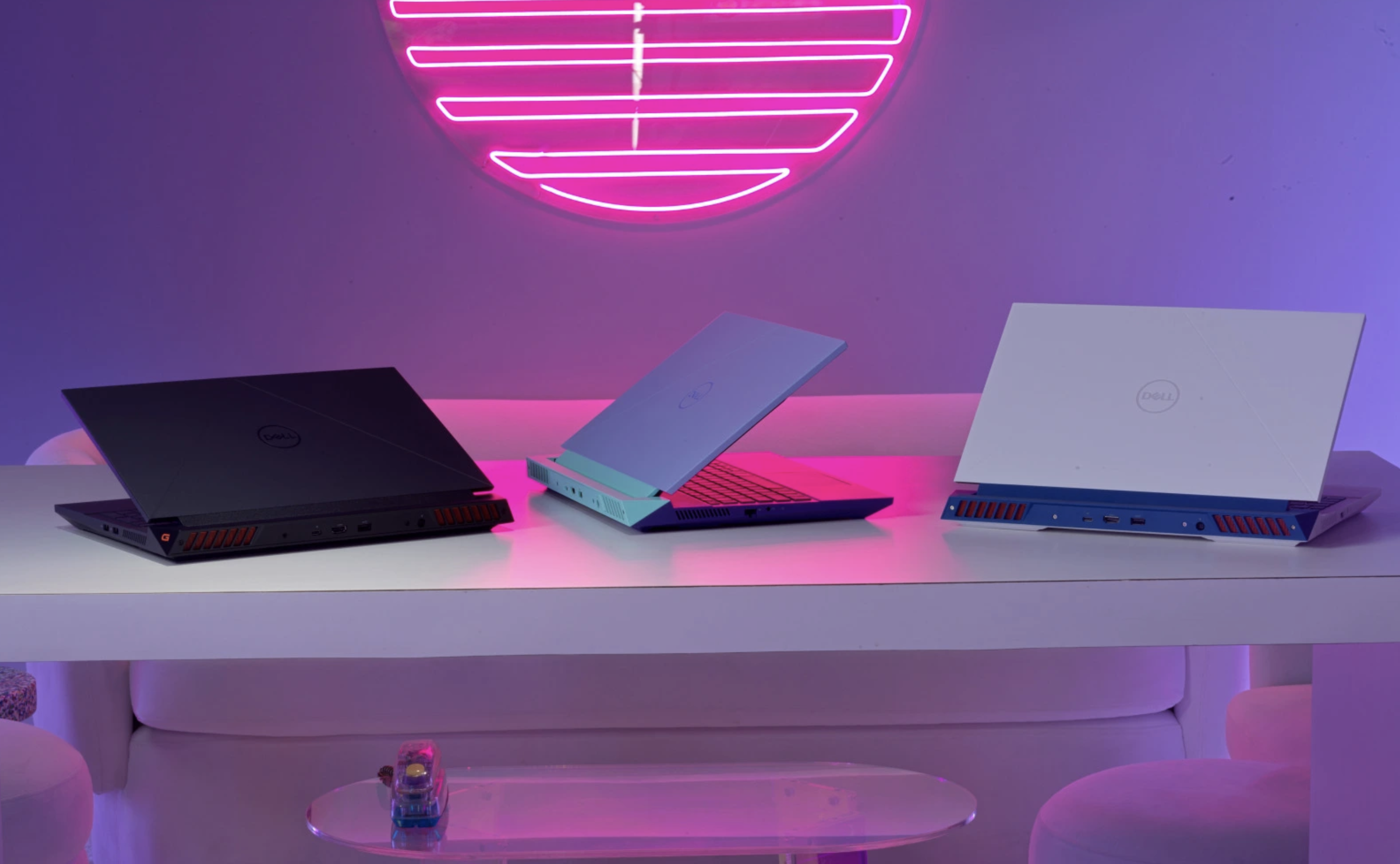 Three different color variants of the Dell G16 gaming laptop on a table.