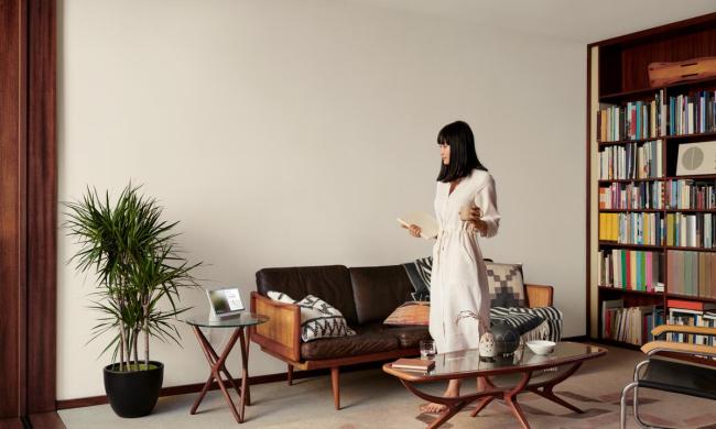 A person standing in a living room while looking at a Google device.