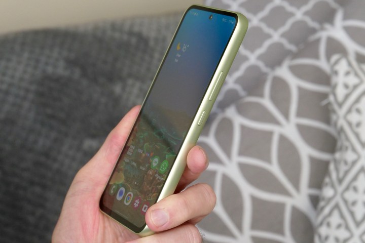 A person holding the Samsung Galaxy A54, seen from the side.