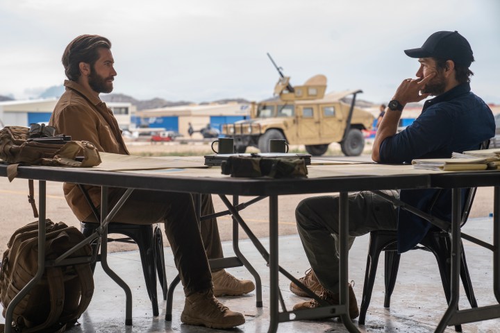 Jake Gyllenhaal and Antony Starr look across a table at each other in Guy Ritchie's The Covenant.