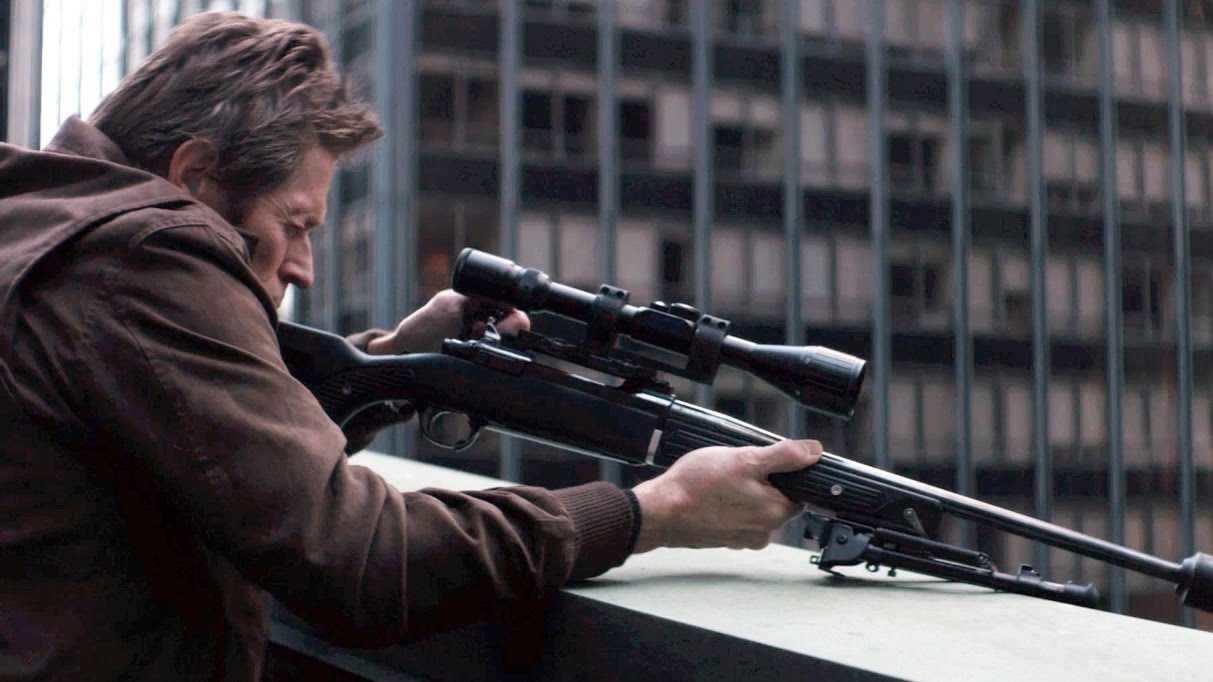 Marcus (Willem Dafoe) mirando um rifle de precisão em John Wick