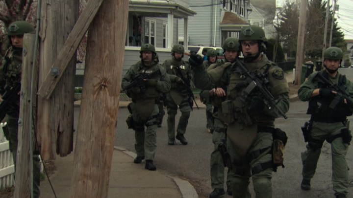 Police in full gear with guns patrolling Boston and surrounding areas in an image from the Boston Marathon bombing in American Manhunt.