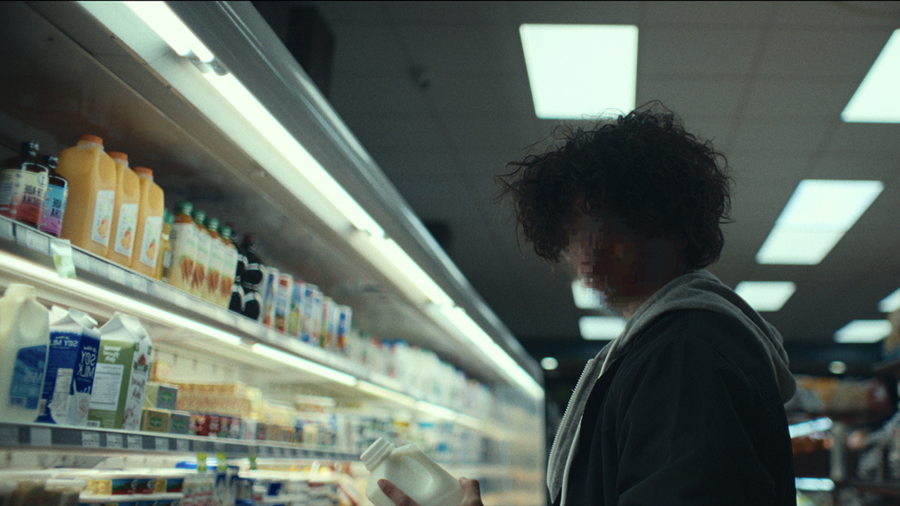 Uma reconstituição de uma cena de American Manhunt, um ator com o rosto pixelado em pé em uma mercearia.