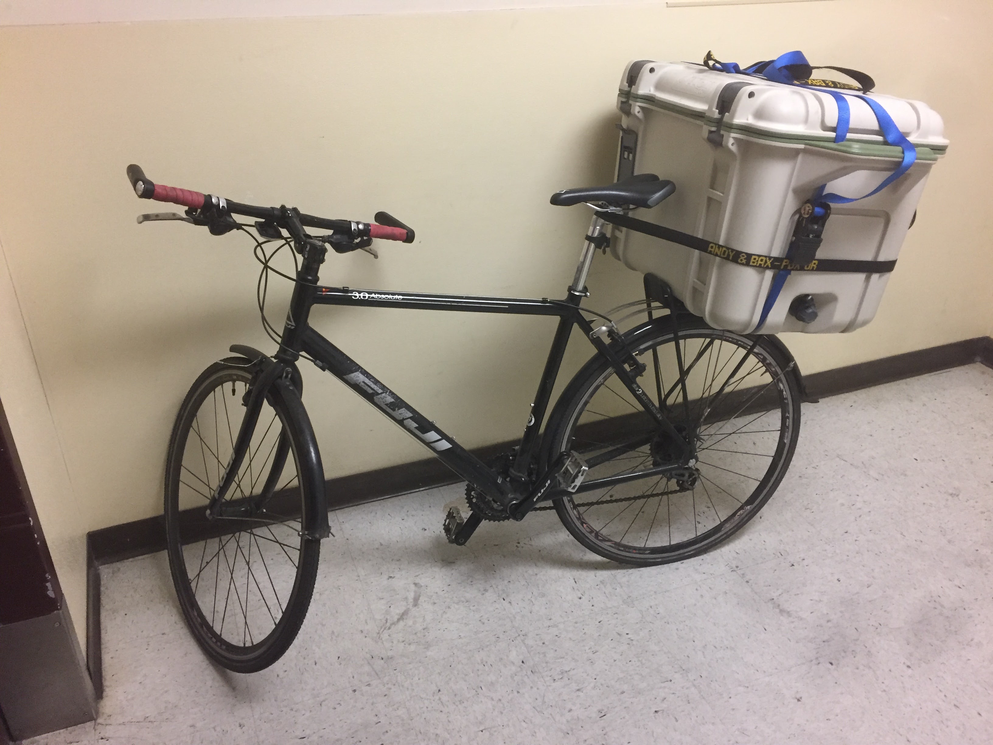Uma bicicleta com um refrigerador amarrado na parte de trás fica em um saguão.