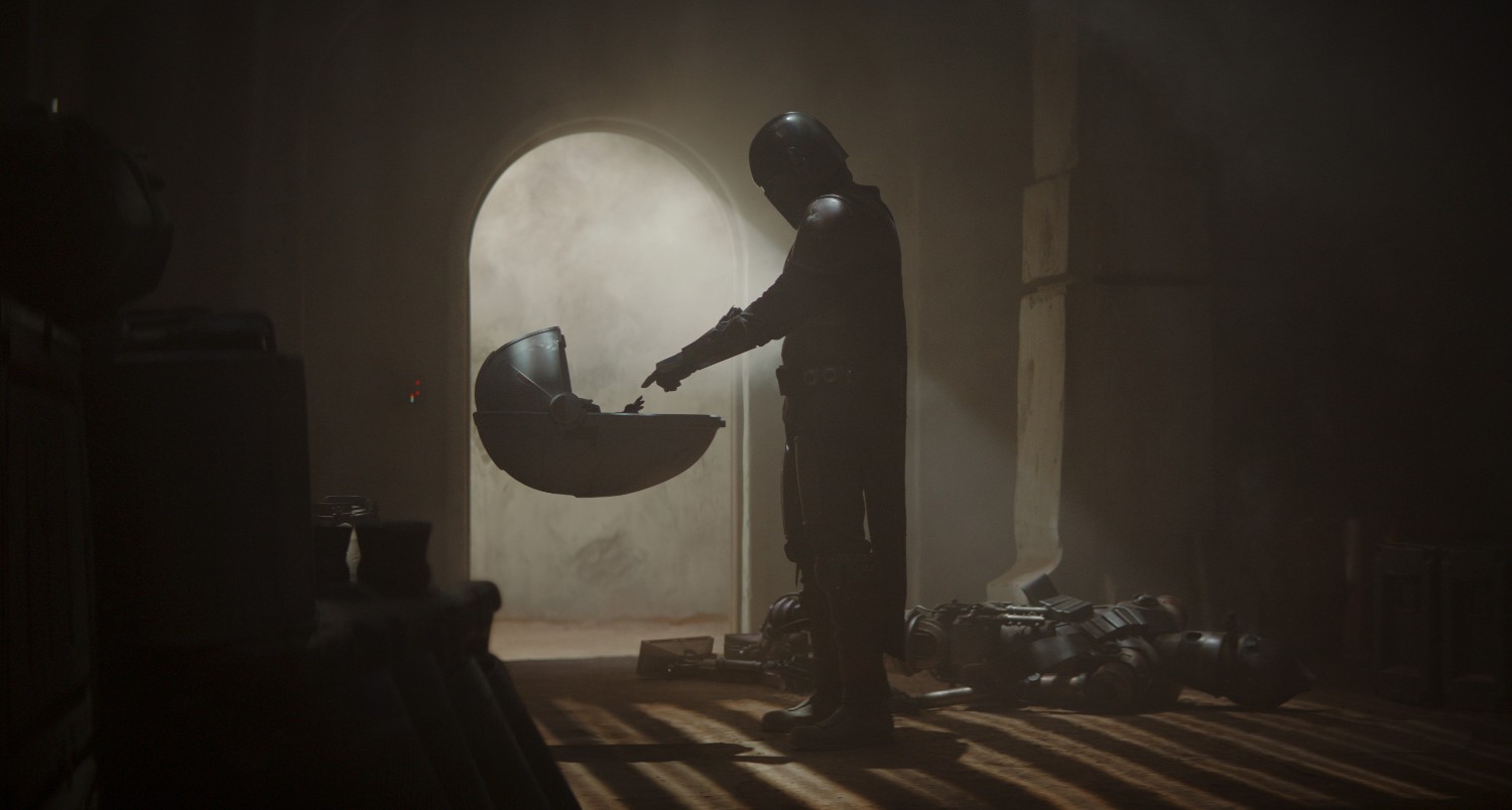 A screenshot from the first episode of The Mandalorian, showing the Mandalorian when he first sees Grogu.