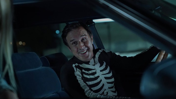 David Arquette as Monty in Mrs. Davis, sitting in a car wearing a skeleton shirt.