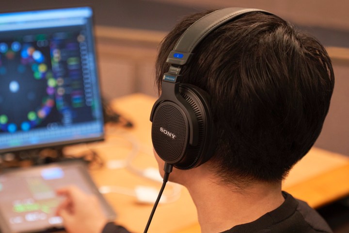 Man wearing Sony MDR-MV1 open-back studio headphones while mixing audio.