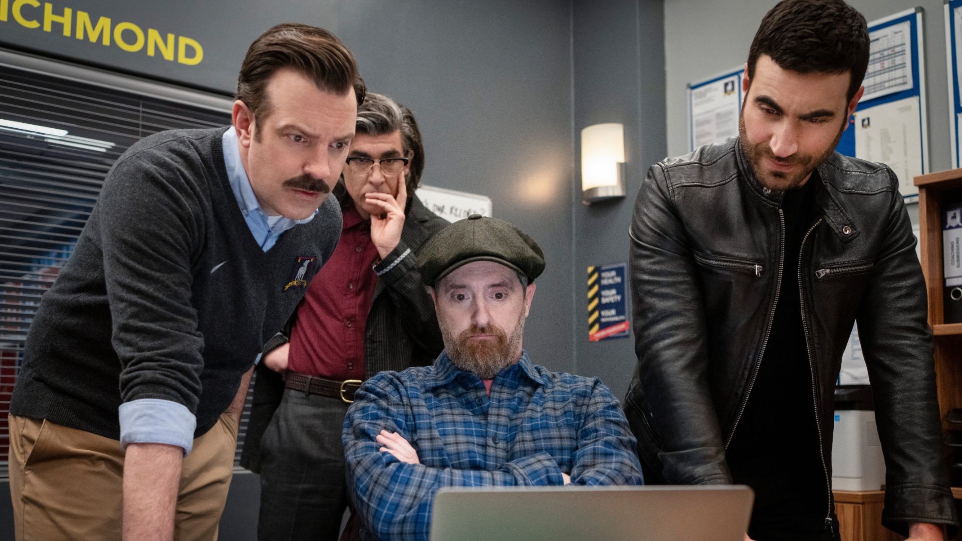 Quatro homens olham para um computador na terceira temporada de Ted Lasso.