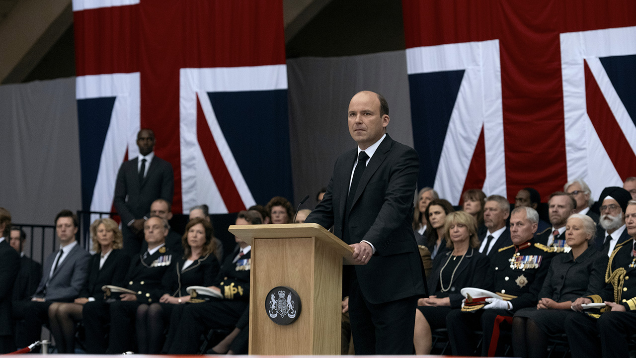 O primeiro-ministro Trowbridge em pé em um pódio em uma cena de O Diplomata na Netflix.