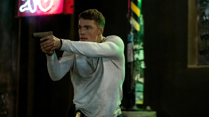 Peter in a white sweater holding a gun in a scene from The Night Agent.