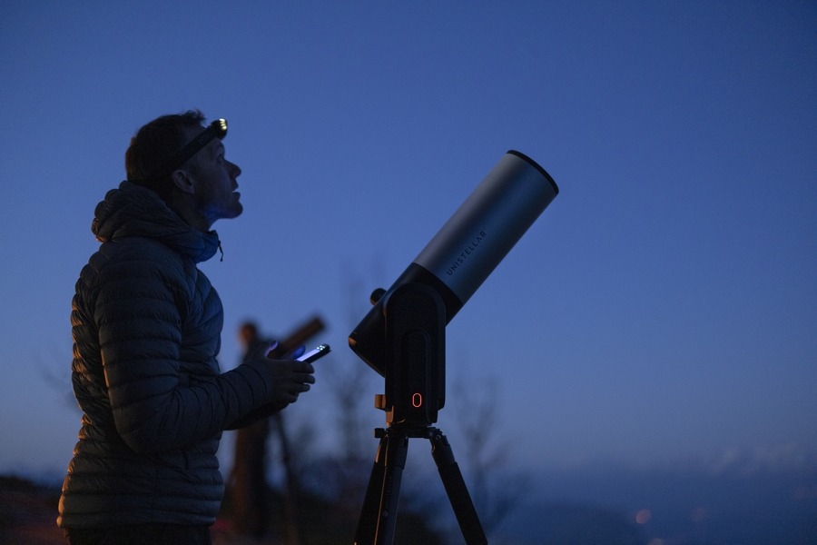 homem com farol olhando para o céu noturno com telescópio