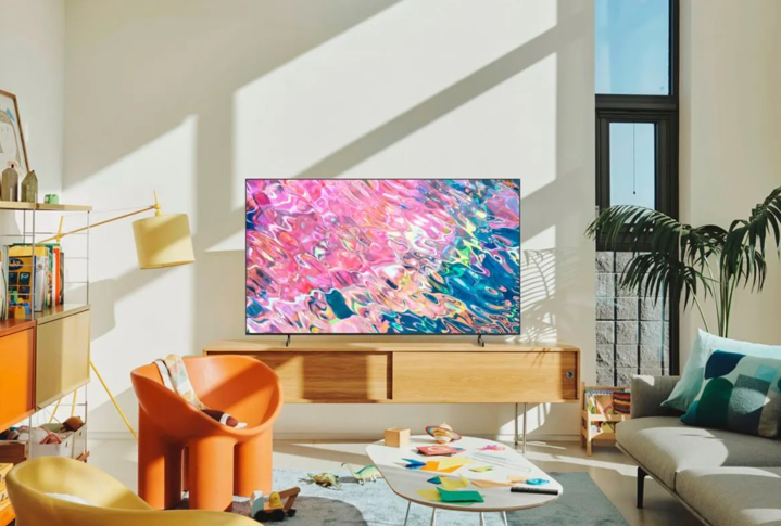 The Samsung Q60B QLED Smart TV sits on a media chiffonier in a active room.