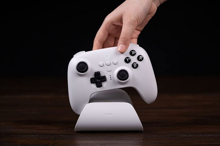 A hand picks up an 8BitDo Ultimate controller.