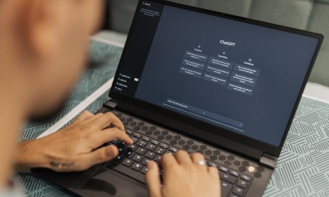 A person typing on a laptop that is showing the ChatGPT generative AI website.