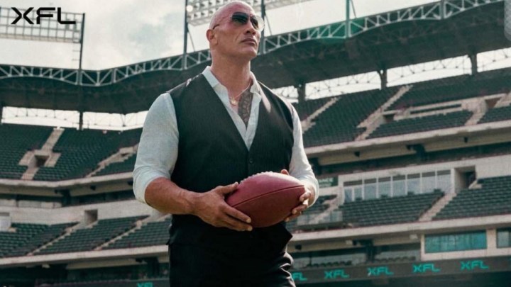 The Rock holds a football for the XFL.