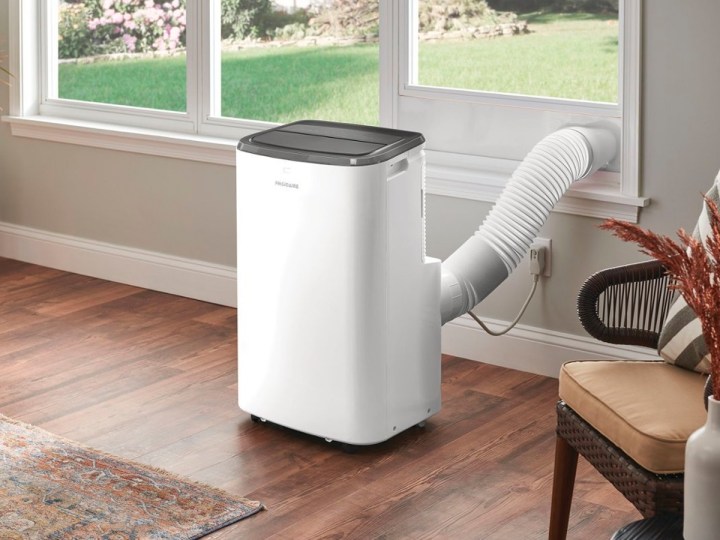 A Frigidaire 3-in-1 portable room air conditioner installed with its exhaust vent connected to the window.