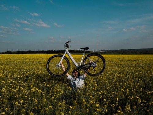 Man holding ebike from Upway in a field, lifestyle image.