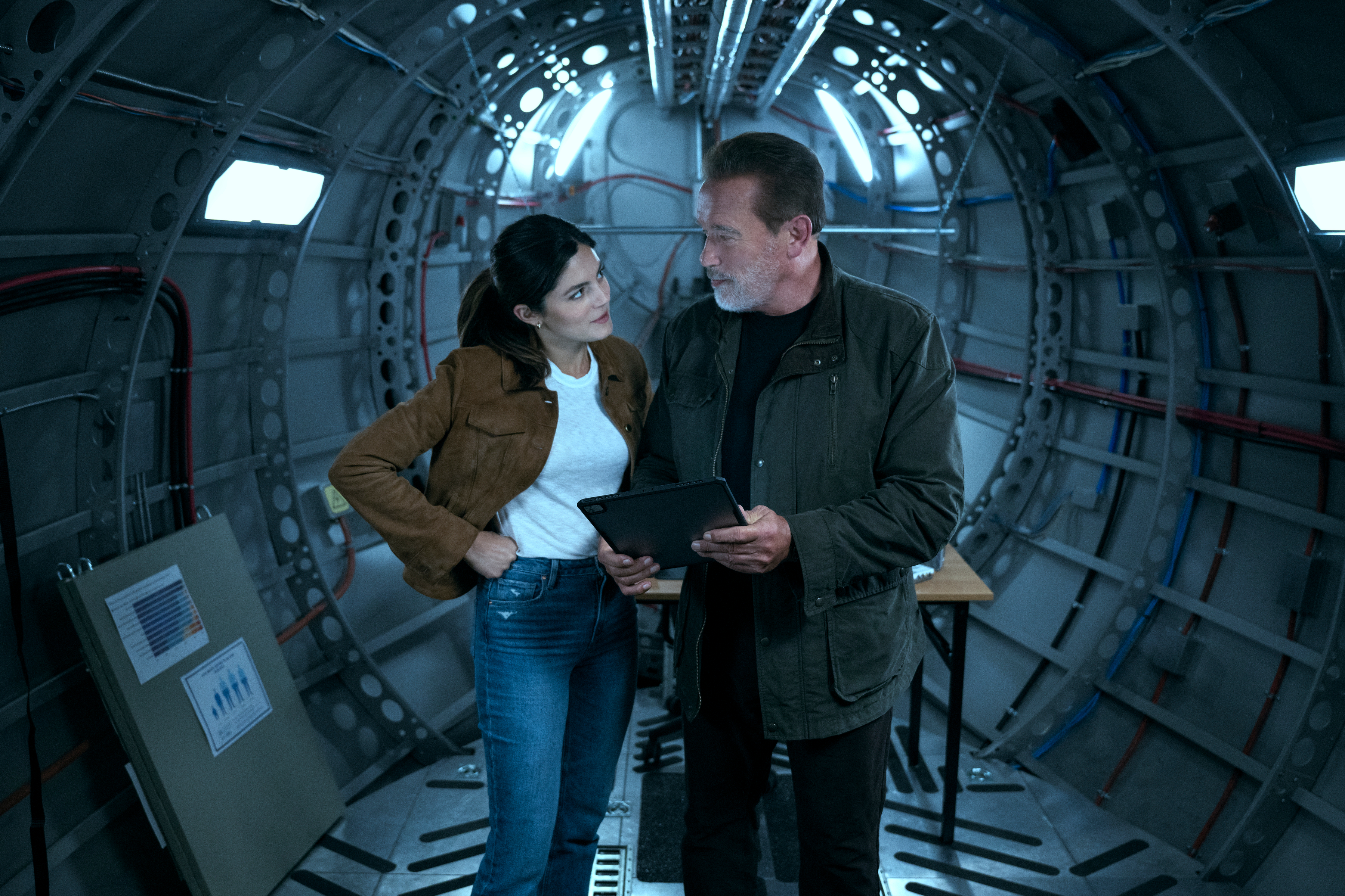 Monica Barbaro e Arnold Schwarzenegger estão juntos em um avião de carga na FUBAR.
