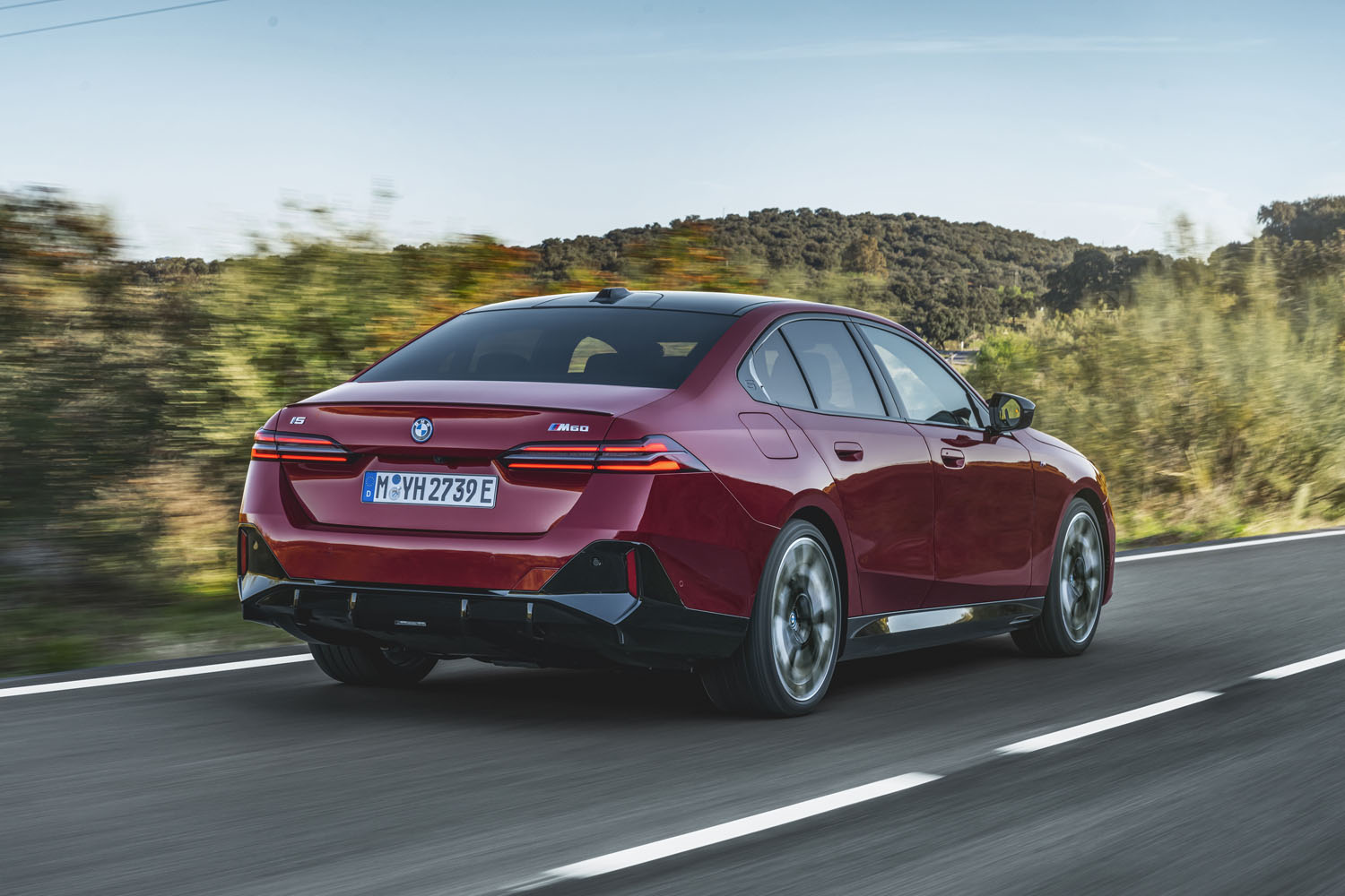A three-quarter view from the rear of a red 2024 BMW i5.