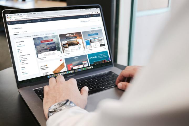 Una persona que usa una computadora portátil en un escritorio con un navegador web que muestra el mercado de HubSpot en su pantalla.