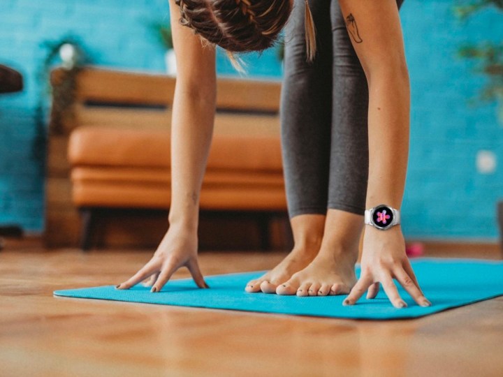 A woman does yoga while wearing a Samsung Galaxy Watch 4.