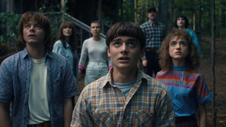 The cast of "Stranger Things" stand next to each other and look up.