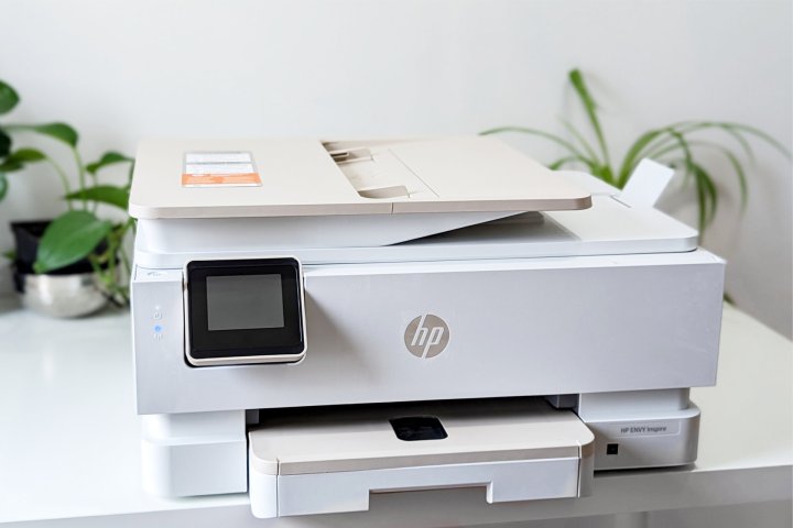 The HP Envy Inspire 7955e rests on a white table with plants in the background.