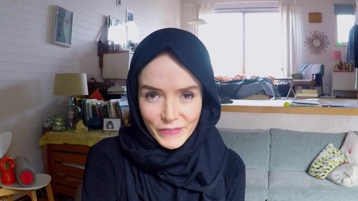 A young woman wearing a hijab and looking at the camera in the movie Profile.