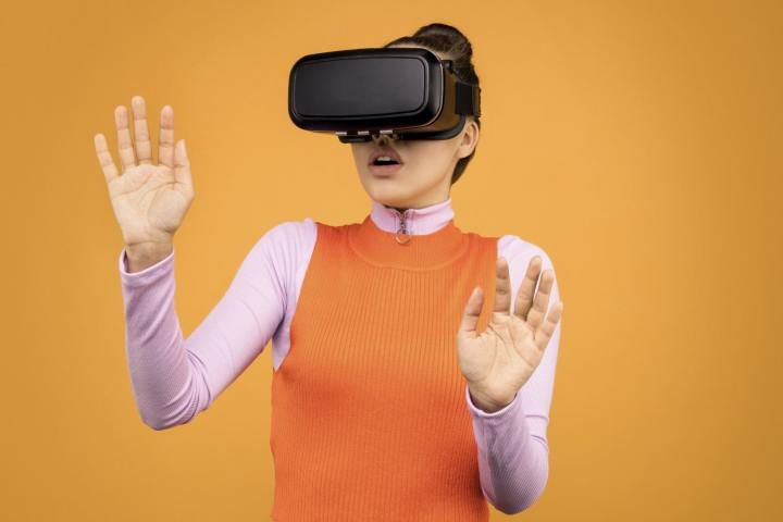 A woman wearing a virtual reality headset against an orange background.