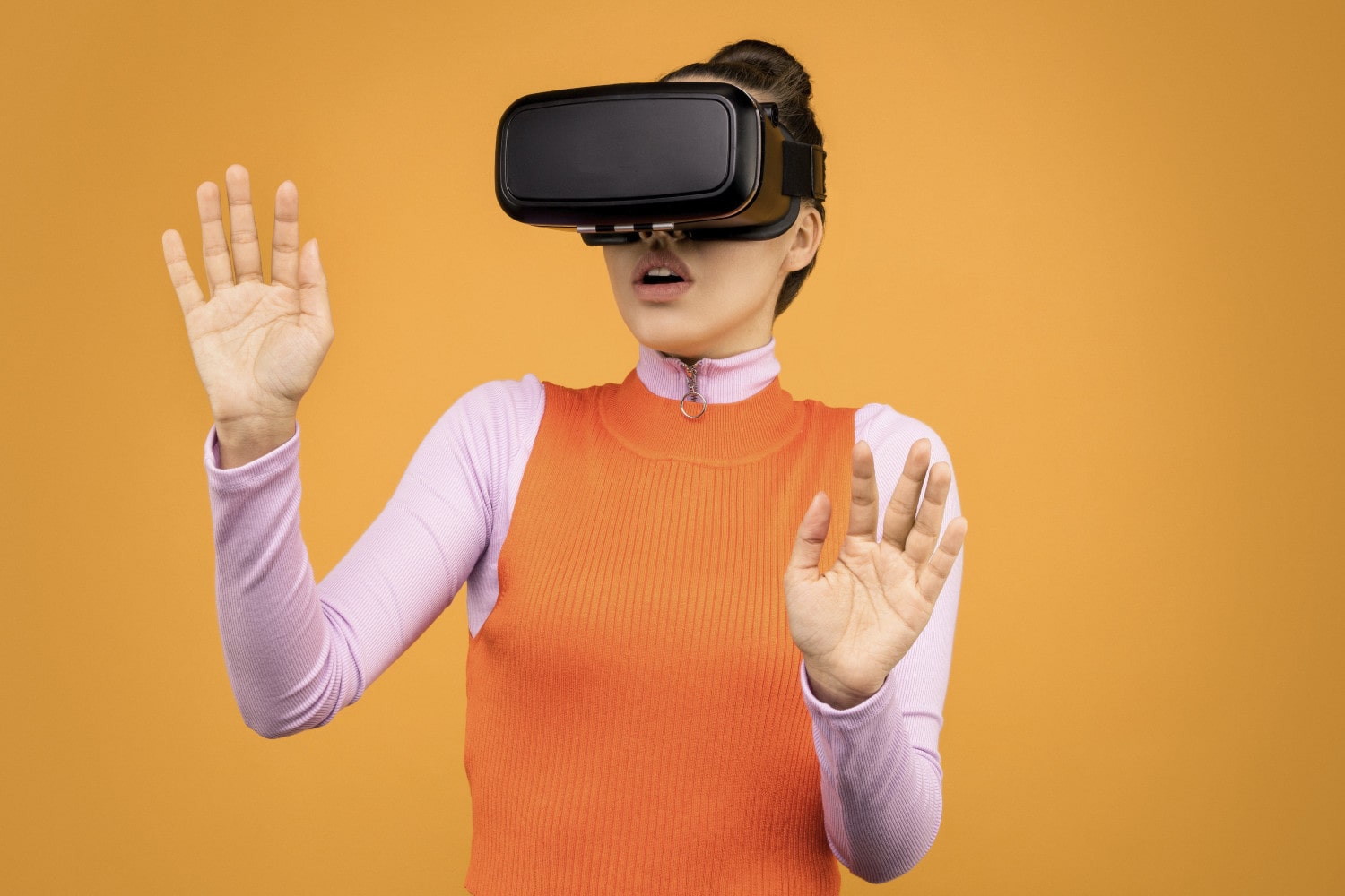 Uma mulher usando um headset de realidade virtual contra um fundo laranja.