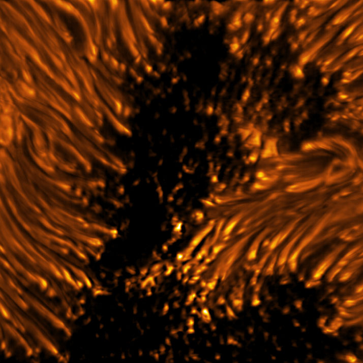 Esta imagem revela as estruturas finas de uma mancha solar na fotosfera.  Dentro da área central escura da umbra da mancha solar, pontos brilhantes de pequena escala, conhecidos como pontos umbrais, são vistos.  As estruturas alongadas que cercam a umbra são visíveis como fios de cabeça brilhante conhecidos como filamentos penumbrais.  Umbra: Região escura e central de uma mancha solar onde o campo magnético é mais forte.  Penumbra: A região circundante mais brilhante da umbra de uma mancha solar caracterizada por estruturas filamentosas brilhantes.