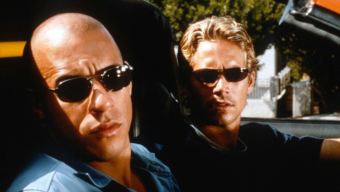 Dois homens olham para fora de um carro em Velozes e Furiosos.