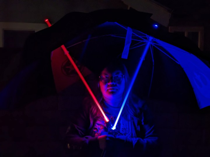 Foto in modalità ritratto notturno di Christine con ombrelli con spada laser scattata con Google Pixel 7a