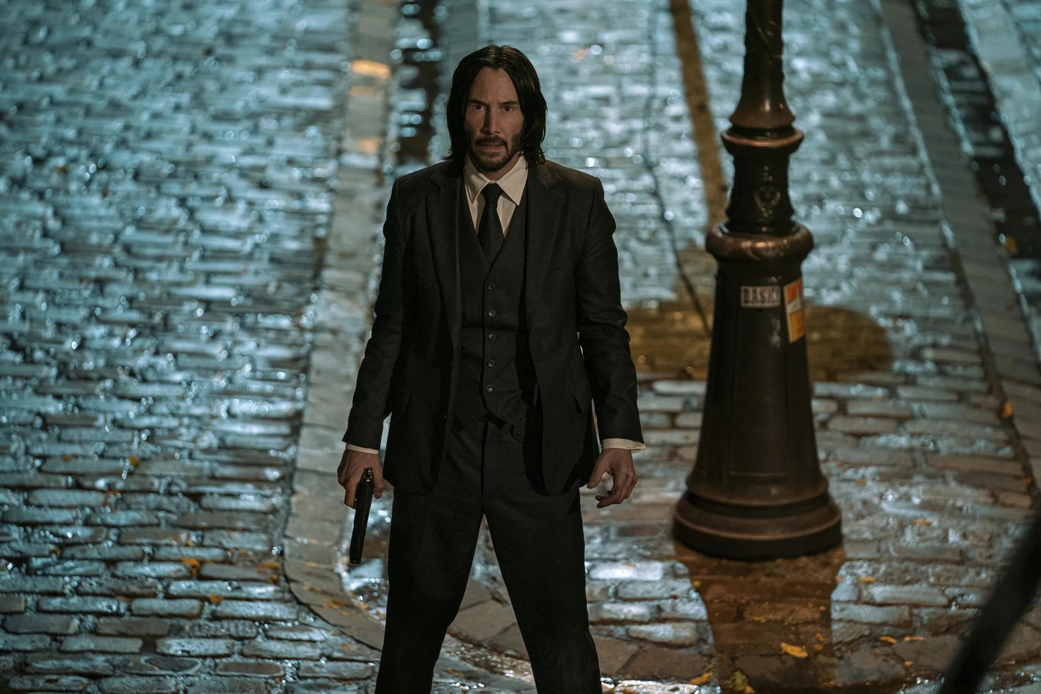 John Wick stands at the bottom of the stairs in John Wick: Chapter 4.