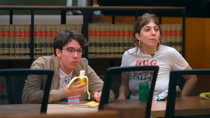 A man eats a banana with a woman on jury duty.