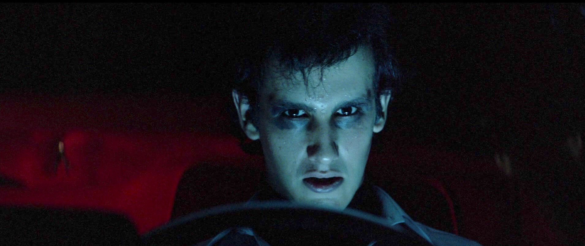 Um adolescente possuído ao volante de um carro olha para Christine.