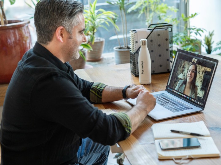 man having work chat from home office with colleagues on screen.