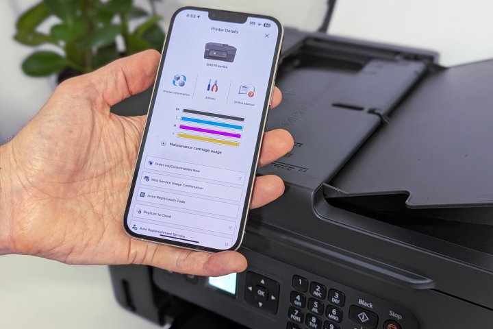 A photo of an iPhone with a mobile app showing check ink levels with a printer in the background.