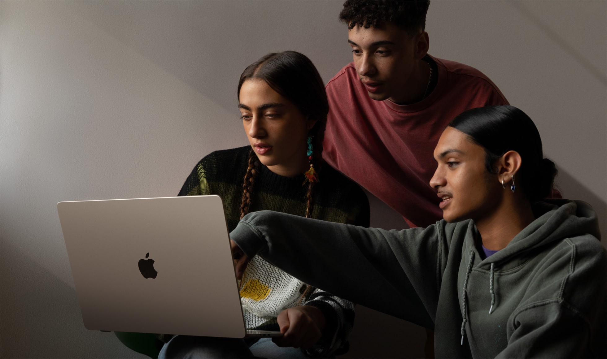 Três pessoas sentam-se em frente a um MacBook Air de 15 polegadas, visto de trás.
