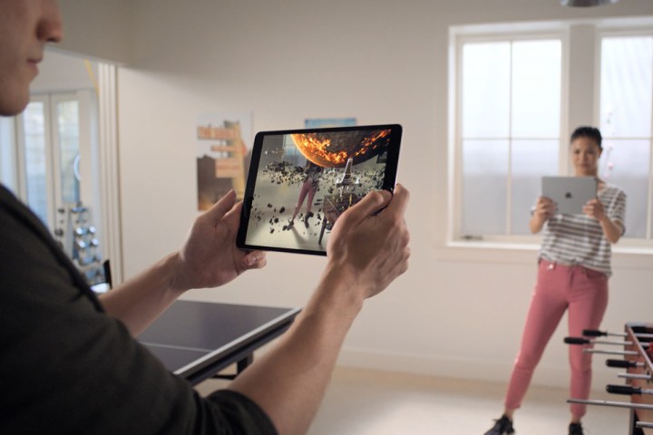 Два человека играют в игру дополненной реальности на Apple iPad.