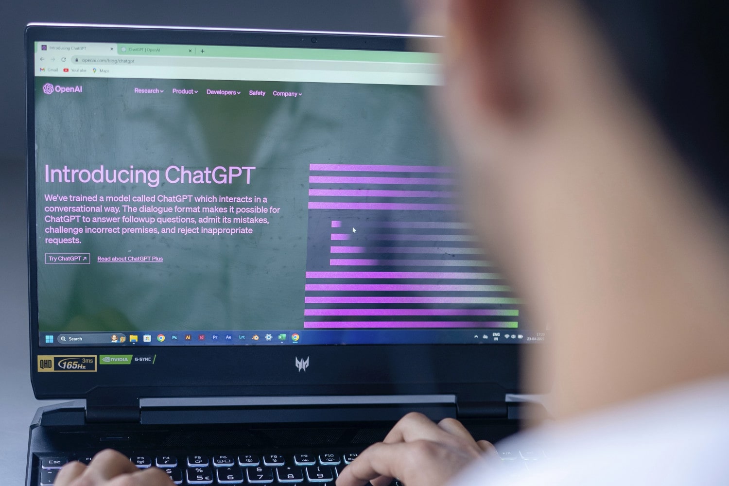 Uma pessoa se senta na frente de um laptop.  Na tela do laptop está a página inicial do chatbot de inteligência artificial ChatGPT da OpenAI.