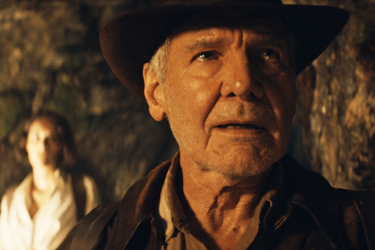 Indy looks at something in a cave in Indiana Jones and the Dial of Destiny.