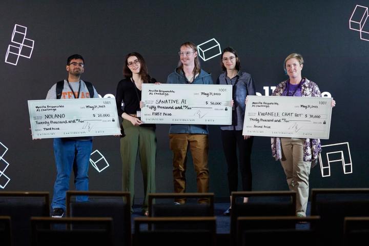 Los ganadores del Desafío de IA Responsable 2023 de Mozilla se paran en un escenario con sus cheques de premio.