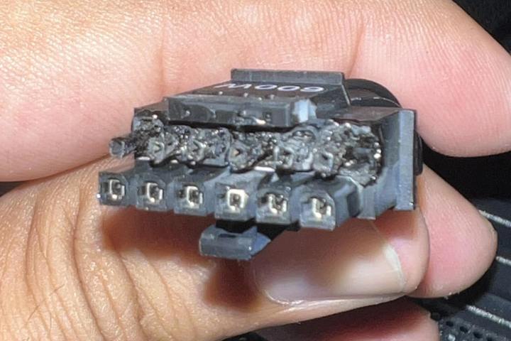 A person holds the connectors of an Nvidia 12VHPWR cable from an RTX 4090 graphics card. The ends of the connectors are burned and melted from where the cable has overheated.