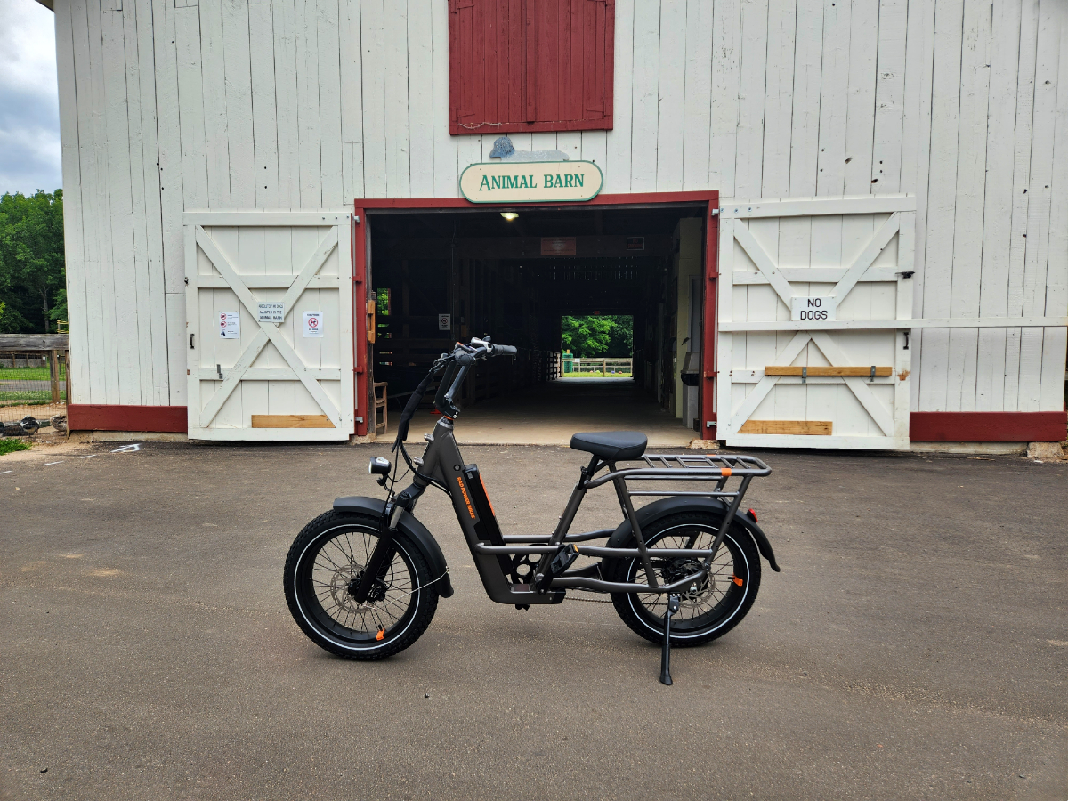 Rad Power Bikes RadRunner 3 Plus parked in front of an animal barn in a park.