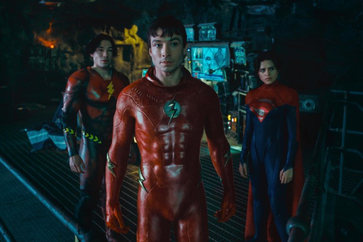 Two versions of Barry Allen stand in the Batcave with Supergirl in The Flash.