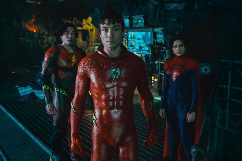 Two versions of Barry Allen stand in the Batcave with Supergirl in The Flash.